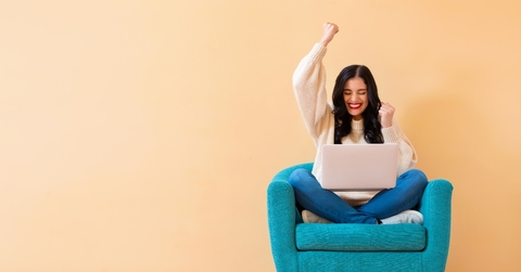 Happy young woman with a laptop sitting in a chair