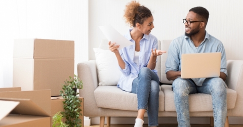 Couple sitting on couch next to moving boxes