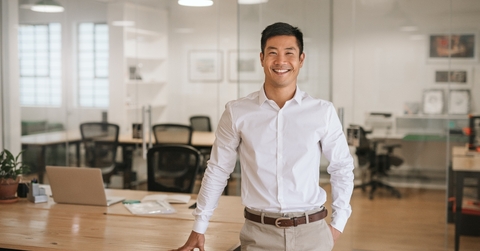 Young Asian businessman standing in an office smiling