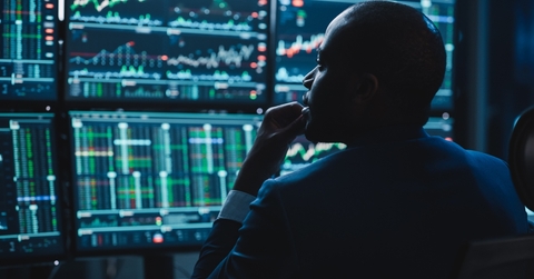 adult man looking at several screens with charts on them