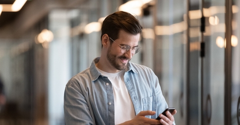 Happy young businessman using smartphone