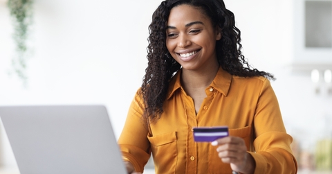 Woman looking at computer holding a credit card