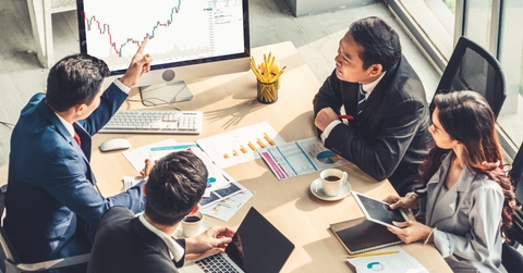 four people at a meeting studying charts