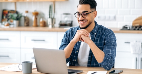 man sitting at a table looking at a laptop