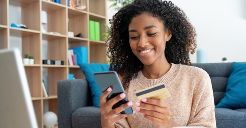 Woman holding credit card and looking at phone