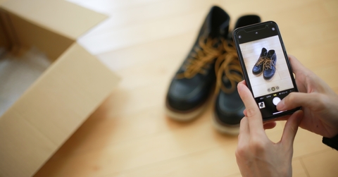 An adult capturing a photo of a pair of shoes using their phone