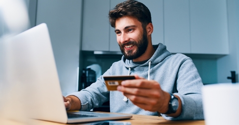 young man paying bills online with credit card and laptop