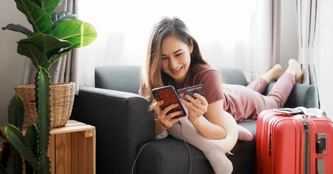 happy woman holding credit card and phone with luggage