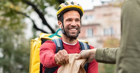 A delivery man handing off a food order.