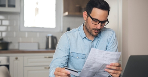business man reviewing bills holding card