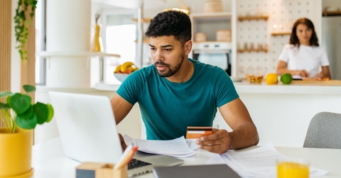 Man holding a credit card and looking at a laptop