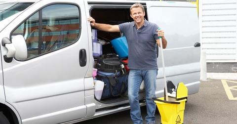 Man standing outside a van holding a mop