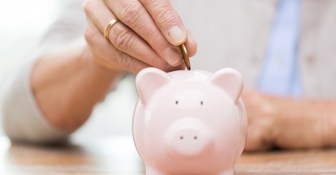 senior woman putting money to piggy bank