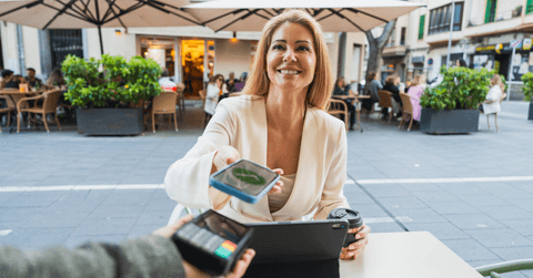 A woman smiles while using her phone to make a payment.