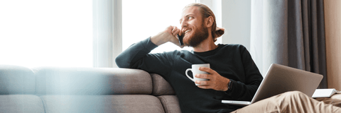 person relaxing on couch with phone and computer