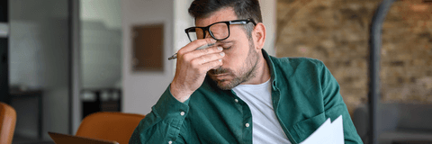 person rubbing eyes at desk