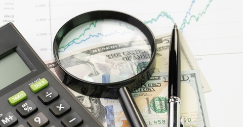 Cash with a yield graph, magnifying glass, calculator, and pen