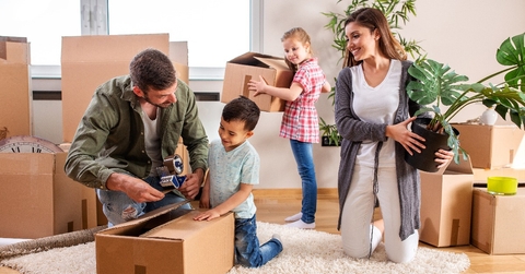 Young couple moving in a new home with their children helping them