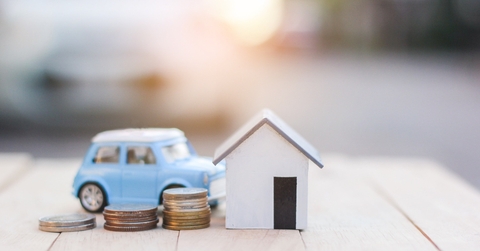 Coins next to a miniature house and car