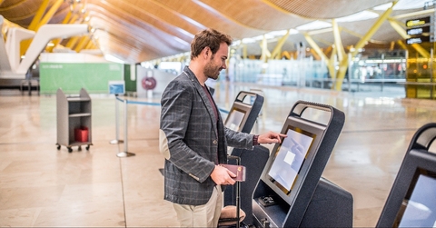 happy man using the check-in machine at the airport getting the boarding pass