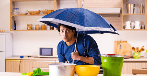 Man with a roof leak standing under umbrella