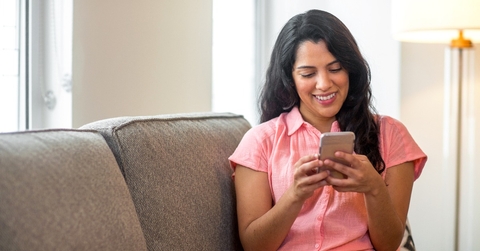 smiling Hispanic woman using her phone at home