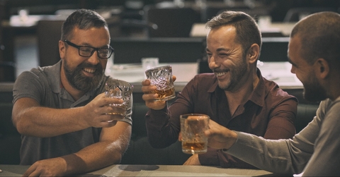 cheerful smiling men holding glasses with alcohol beverages and laughing