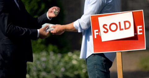 People shaking hands by &#x27;sold&#x27; house sign
