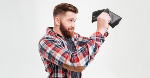 young man in plaid shirt looking inside his empty wallet