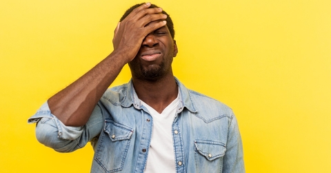 regretful man in denim casual shirt holding hand on face