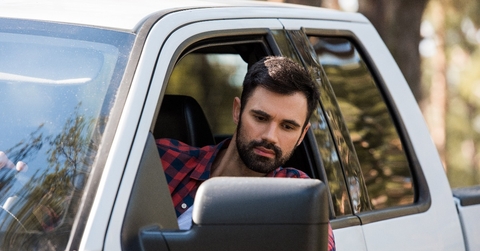 handsome bearded man driving pickup truck in forest
