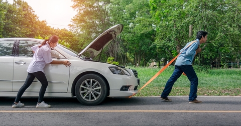 young woman pushing a car while the man is pulling the car
