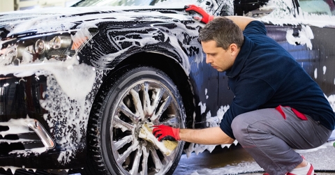 Man worker washing car&#x27;s alloy wheels on a car wash