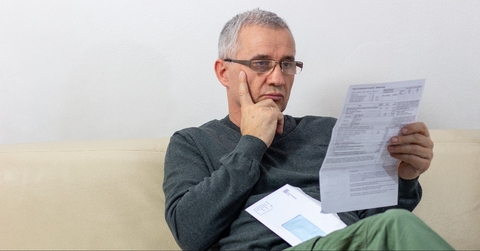 Worried middle-aged man reading unexpected news in paper document