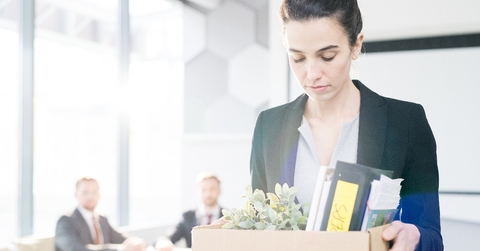 woman holding box of personal belongings leaving office
