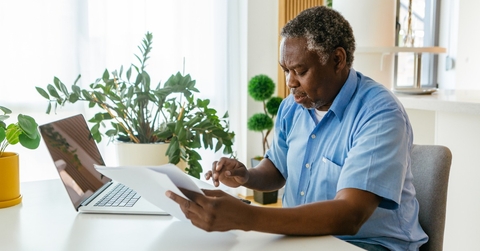 man sitting in his home office with bills in hands