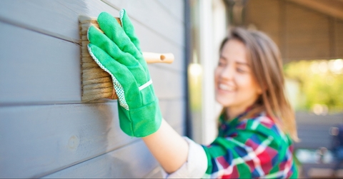 Cheerful woman applying protective paint