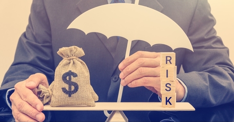 businessman holds a white umbrella protects a dollar bag on basic balance scale