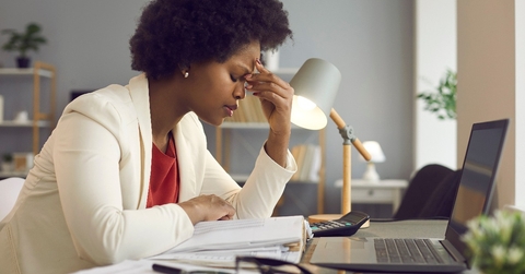 woman keeping eyes closed and massaging nose after working at laptop