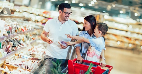 family with child and shopping cart buying food at grocery store