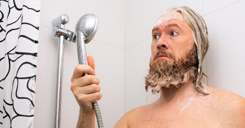 bearded man with soapy head standing in the bathroom