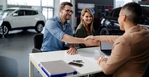 male customer and female car dealer shaking hands at showroom