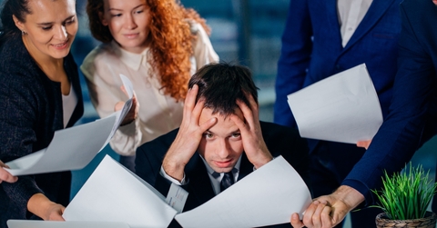 various employees giving out papers to a frustrated employee in an office