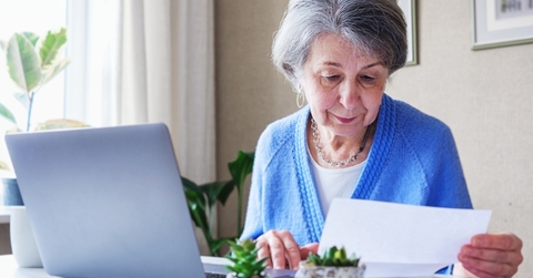 senior lady reading document and working on laptop