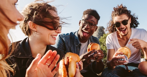 group of friends eating burger on mountain top