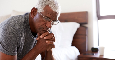 depressed senior man looking unhappy sitting on side of bed