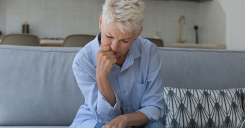 upset older woman sit on sofa manages finances