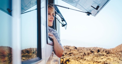 Woman smiling with head and arm over open RV window