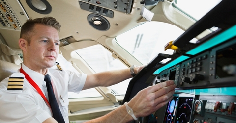 male pilot checking control panel in airplane cockpit