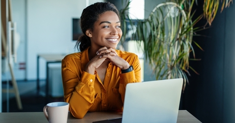 businesswoman sitting at desk in office and thinking while working on laptop